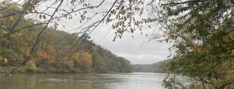 The Flint river flows upstream in the fall with a dark and cloudy sky.